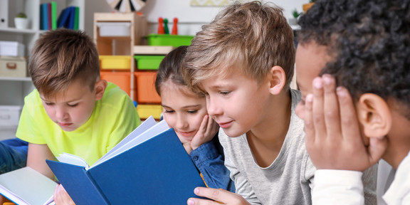 Kinder mit Buch Vier Kinder schauen in ein Buch