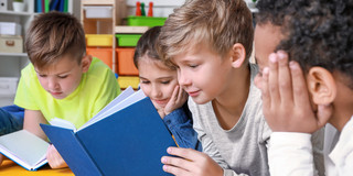 Kinder mit Buch Vier Kinder schauen in ein Buch
