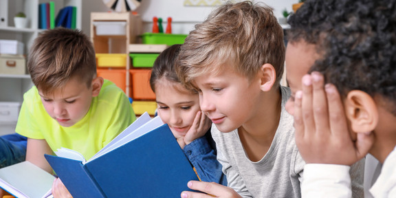 Vier Kinder schauen in ein Buch