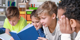Vier Kinder schauen in ein Buch