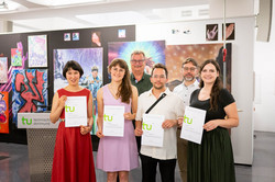 Auf dem Bild sind Prof. Gerhard Schembecker, Dr. Niklas Gliesmann sowie die Preisträger*innen Dulana Tillmann, Marie Schütte, Daniel Friedt und Lucy Pawlowicz zu sehen. Die Preisträger*innen halten ihre Auszeichnung vor ihrem Oberkörper. Im Hintergrund befindet sich eine schwarze Wand mit verschiedenen Kunstwerken.