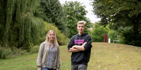 Polina Mihal und Mikhail Krigman Eine Frau und ein Mann stehen nebeneinander auf einer Wiese.