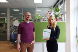 Sommersemester Ein Mann steht neben einer Studentin, die ein Zertifikat in den Händen hält.