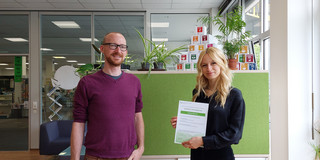 A man stands next to a student holding a certificate in her hands.