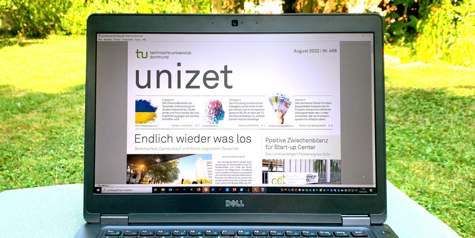 Ein Laptop steht auf einem Tisch, der auf einer Grünfläche am Campus der TU Dortmund aufgestellt wurde. Auf dem Monitor des Laptops ist ein Fenster mit einer Ausgabe der unizet geöffnet.