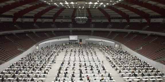 Westfalenhallen Blick von oben in eine Konzerthalle, in der viele Tische aufgebaut sind, an denen Personen sitzen.