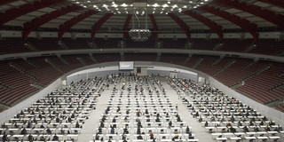 Westfalenhallen Blick von oben in eine Konzerthalle, in der viele Tische aufgebaut sind, an denen Personen sitzen.