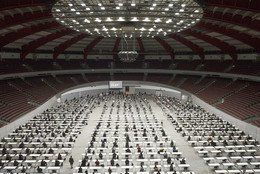 Blick von oben in eine Konzerthalle, in der viele Tische aufgebaut sind, an denen Personen sitzen.