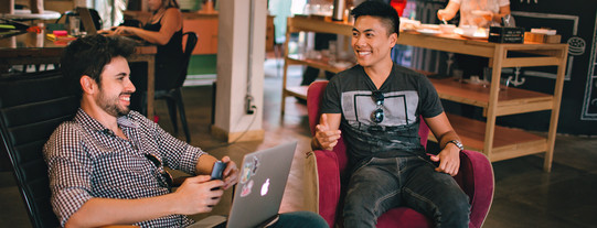 Coworking Zwei Männer sitzen in Sesseln, einer von ihnen hat ein Laptop auf dem Schoß.