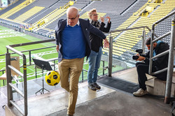 Ein Mann schießt einen Fußball in eine Tribüne gefüllt mit Erstsemesterstudierenden.