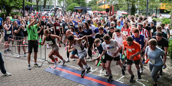 Start Staffellauf Viele Menschen mit Staffelstäben laufen gleichzeitig über die Startlinie