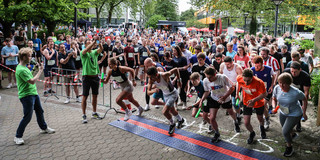 Start Staffellauf Viele Menschen mit Staffelstäben laufen gleichzeitig über die Startlinie