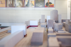 The picture shows an architectural model made of wood. Among other things, Dortmund Central Station and the city library are recognizable. Pictures can be seen on the wall in the background.