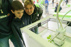 Zwei Besucher sehen interessiert einem 3D-Drucker beim Drucken zu
