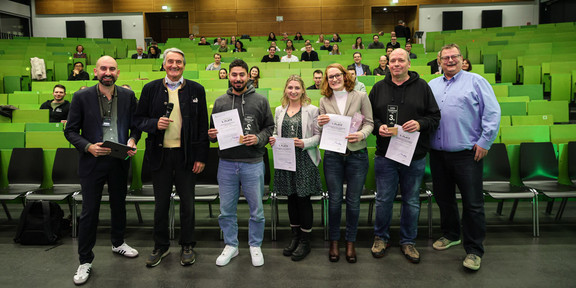 Gruppenfoto mit sieben Personen vor Publikum im Hörsaal