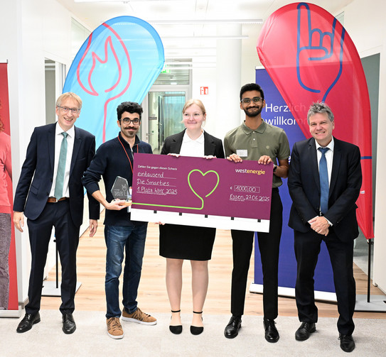 Gruppenfoto: Zwei Studierende halten ihre Auszeichnung für den Westenergie Manager Cup in den Händen. Zwei Professoren stehen jeweils rechts und links am Rand.