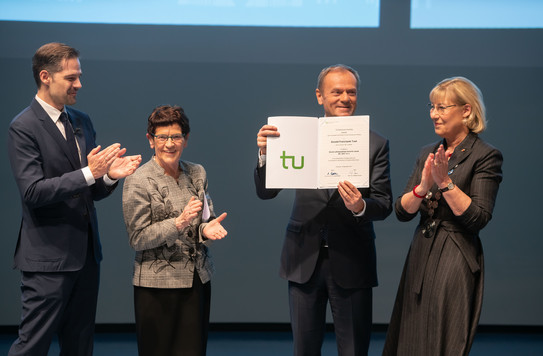 Gruppenbild von zwei Frauen und zwei Männern, von denen einer eine Urkunde hält.