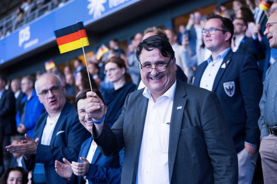 Menschen stehen im Stadion und blicken auf das Geschehen der Eröffnungsfeier.