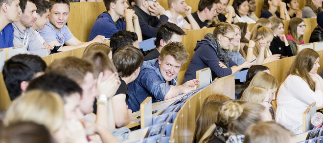 Gruppe von Studierenden im Hörsaal, Im Fokus ein junger Mann der lacht