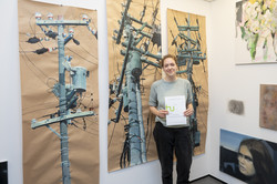 Eine Studentin steht vor drei großen Gemälden auf Packpapier.