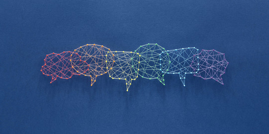 Several speech bubbles are pinned on a dark blue nail board with different colored threads.