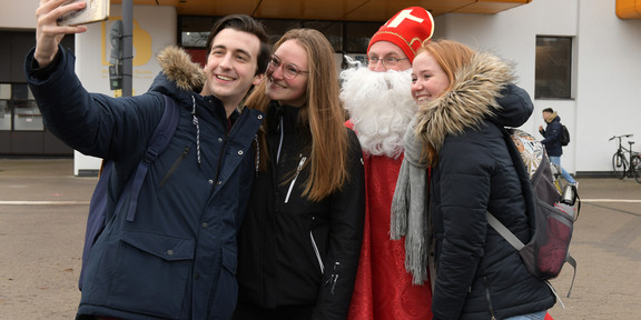 Nikolaus Drei Studierende machen ein Selfie mit einem Mann, der als Nikolaus verkleidet ist.