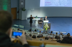 Vortragsreihe „Initialzündung“ Ein Mann hält in einem mit Studierenden gefüllten Hörsaal einen Vortrag, der von einer Dame in Gebärdensprache übersetzt wird.