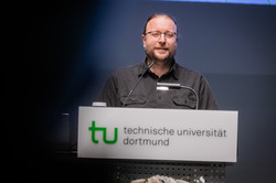 Photo: Prof. Sascha Pöhlmann stands at the lectern during the TU Dortmund University's annual academic ceremony.