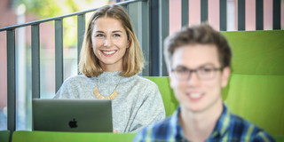 Zwei Studierende sitzen in einem Hörsaal.