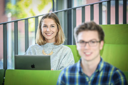 Zwei Studierende sitzen in einem Hörsaal.