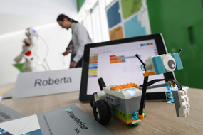 Ein Lego-Roboter und ein Laptop stehen auf einem Tisch, auf einem Schild daneben steht "Roberta"
