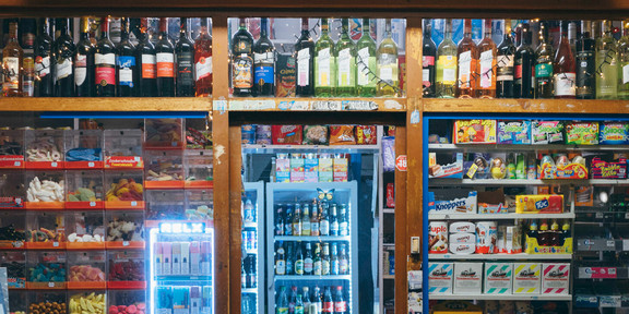 Zu sehen ist ein Kioskschaufenster mit einer Leuchtreklame "Export, Union, Pilsner" steht.