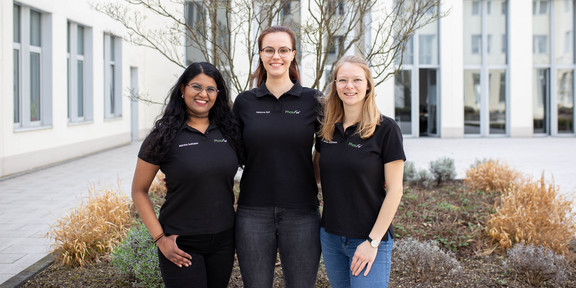 Portrait_FemaleFounders_PhosFad Porträtfoto der Studentinnen Abirtha Suthakar, Fabienne Ryll und Ronja Weidemann der Fakultät Bio- und Chemieingenieurwesen vor einem weißen Haus mit Beet