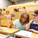 Kinder sitzen in den Reihen eines Hörsaals und bearbeiten Mathematikaufgaben mit Spaß und Spannung - Trickspiele 