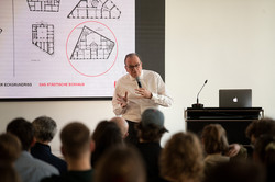 Eine Person spricht an einem Rednerpult mit Laptop und Mikrofon.