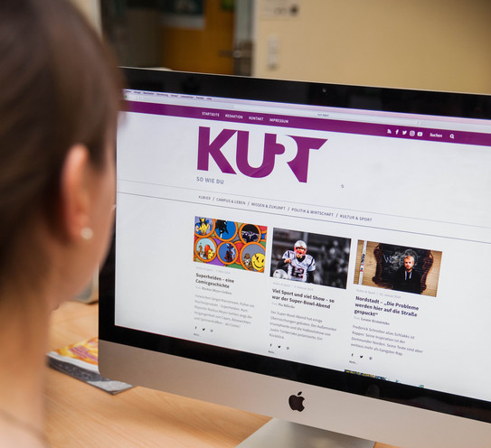 Kurt Webseite Eine Frau sitzt vor einem Computer und auf dem Bildschirm wird die Seite KURT angezeigt.