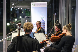 Zwei Frauen und zwei Männer spielen sitzend ihre Streich-Musikinstrumente auf einem Podium, vor ihnen stehen Notenständer.