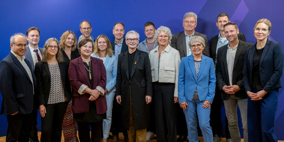 Gruppenbild mit Dr. Petra Bahr und den 15 Mitgliedern des Bundesjugendkuratorium vor blauem Hintergrund: Prof. Nele McElvany ist die dritte Person von Links.