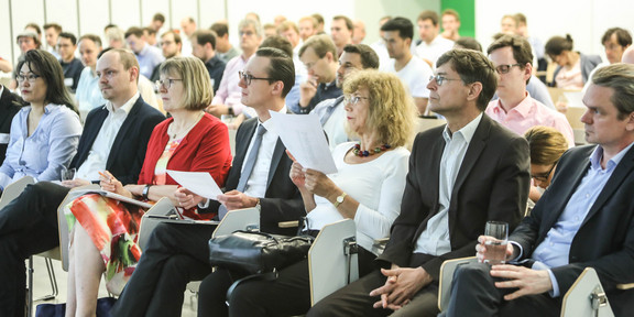 Blick ins Publikum, das einen Vortrag auf der Bühne verfolgt