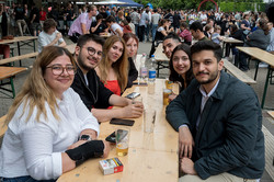 mehrere Personen sitzen an einem Tisch und lächeln in die Kamera