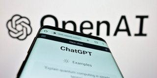 ChatGPT Ein Smartphone, auf dem die Webseite "ChatGPT" geöffnet ist, vor einem Logo von OpenAI.
