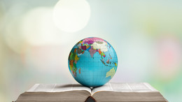 Ein Globus liegt auf einem aufgeschlagenen dicken Buch
