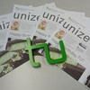Mehrere Ausgaben der Unizet liegen auf einem Tisch. Darauf ist ein TU-Logo abgelegt.