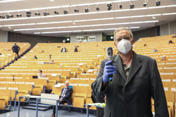 A man wearing a mouth guard and protective gloves holds a microphone in his hand, which is protected by a foil