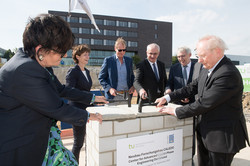 Several people stand around a brick cube and close it with hammers.