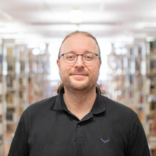Portrait Sascha Pöhlmann Portrait eines Mannes in einer Bibliothek