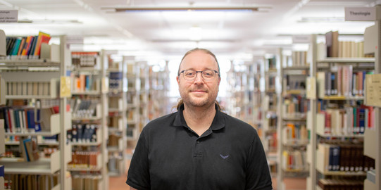 Portrait Sascha Pöhlmann portrait of a man in a library