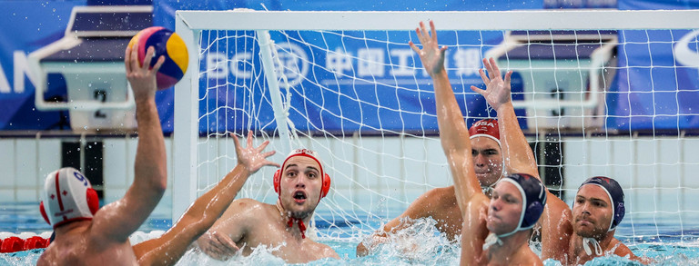 Szene eines Wasserball-Spiels: Ein Arm ist in der Luft, bereit zum Wurf, andere Hände wehren ab