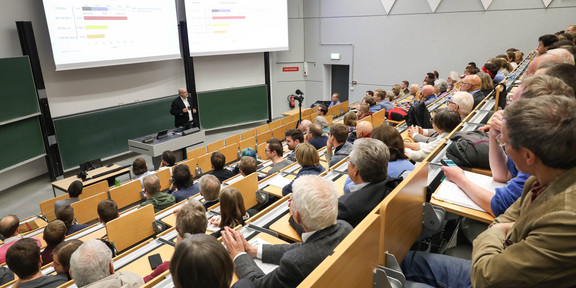 Auftakt zur Vorlesungsreihe „Fridays for Future“ Voller Hörsaal mit Menschen aus allen Altersklassen, die einem Vortrag zur Energiewende zuhören.