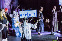 Darsteller hält ein "Applaus"-Schild hoch